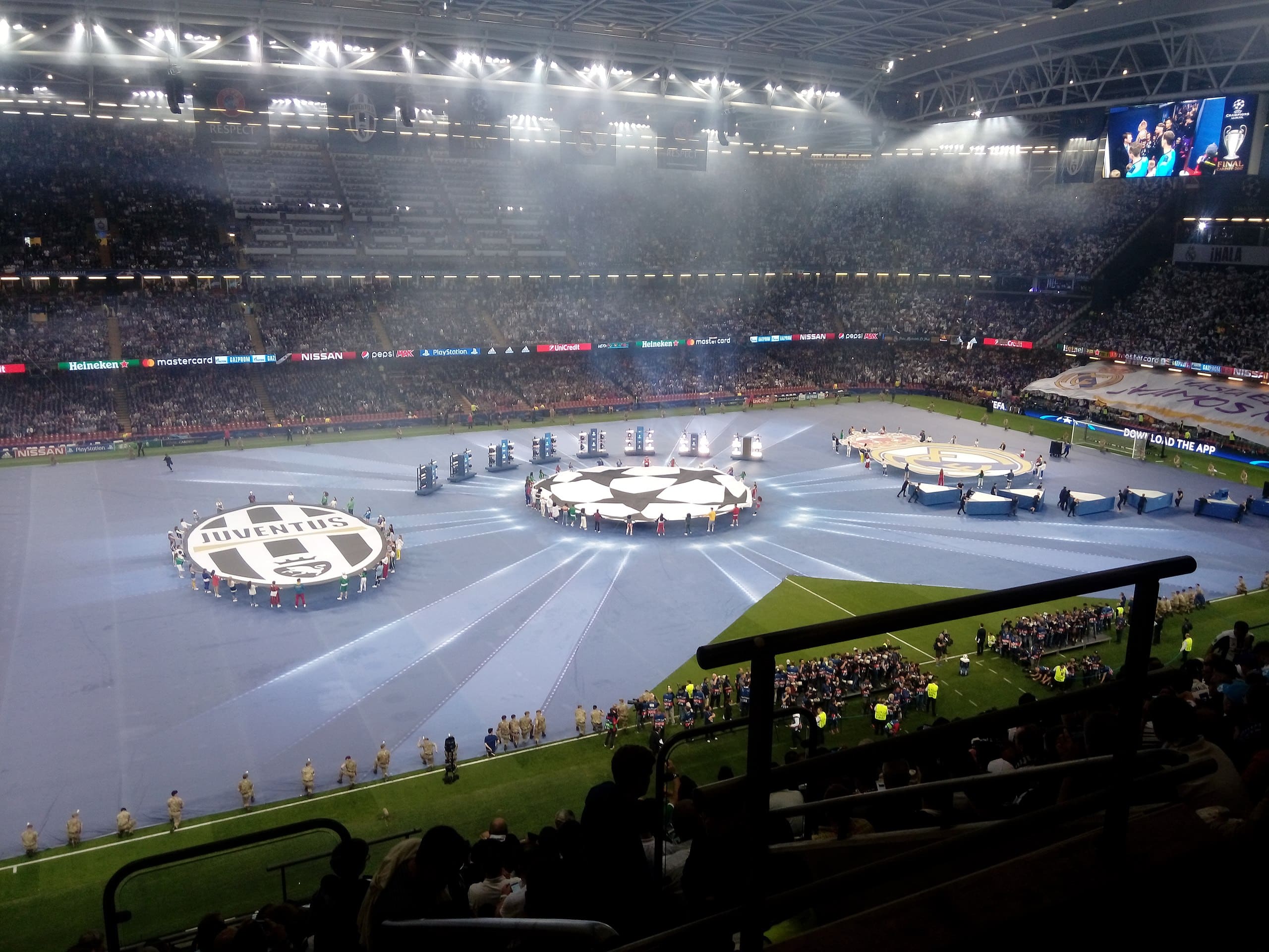 Opening ceremony of the UEFA Champions League Final 2017 in Cardiff, with Juventus and Real Madrid logos displayed on the field in front of a packed stadium.